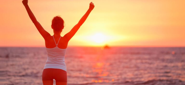 Happy cheering celebrating success woman at beautiful beach sunset