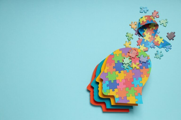 Mental Health Is a Leadership Imperative in Construction A colorful puzzle-piece illustration of a human head silhouette with pieces scattered above, symbolizing mental health awareness on a light blue background.