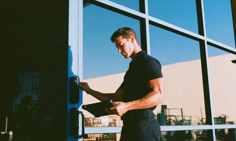 How to Bulletproof Your Home Security A rugged male security consultant in a fitted black polo shirt and tactical pants confidently pressing his thumb against a sleek matte black biometric smart lock on a modern glass front door