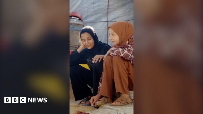 Teenager shows BBC life inside Gaza displacement camp Two young girls sat on a step. One (left) is dressed in all black, the other (right) is dressed in light brown.